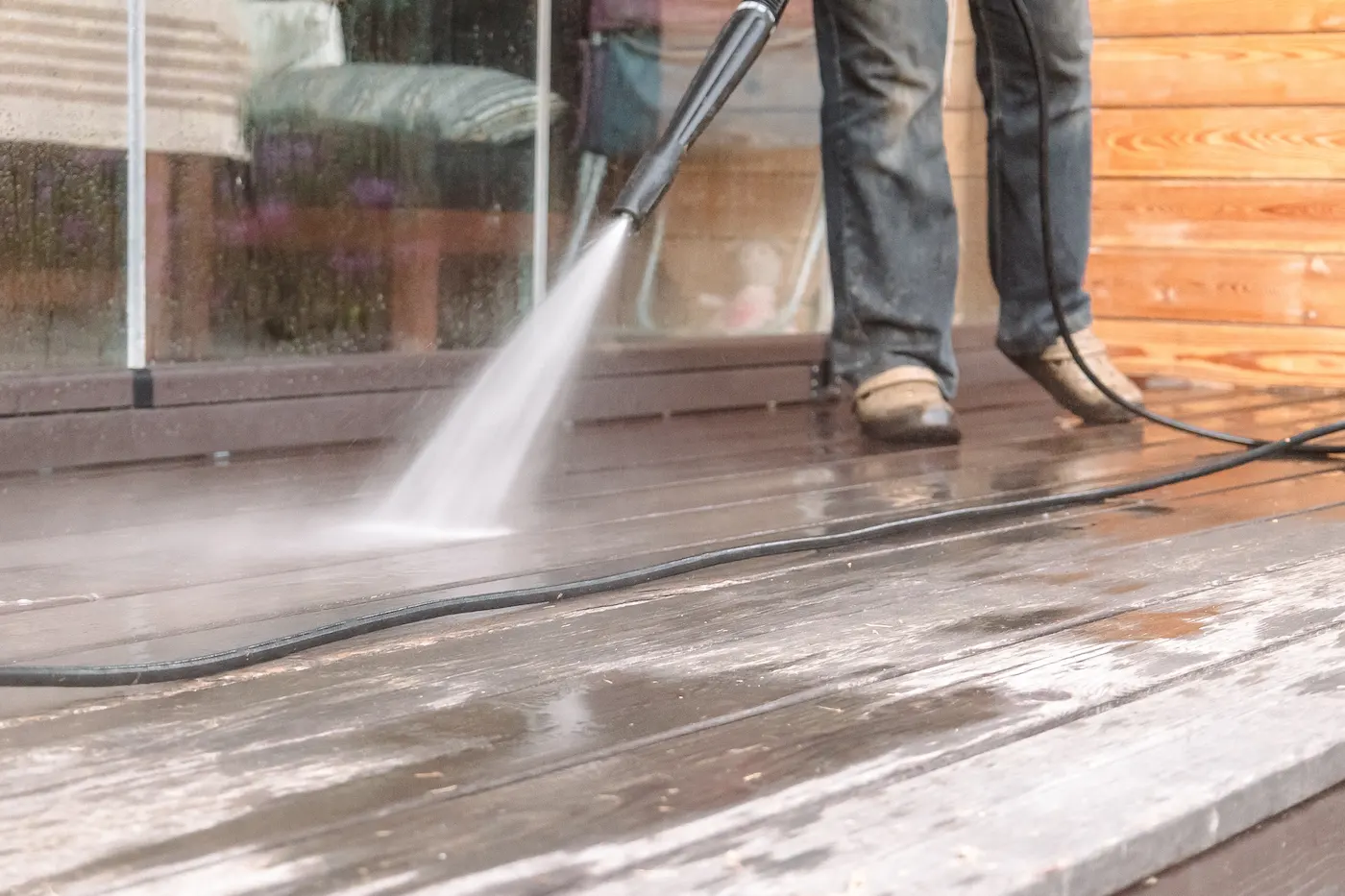 man pressure washing wooden deck