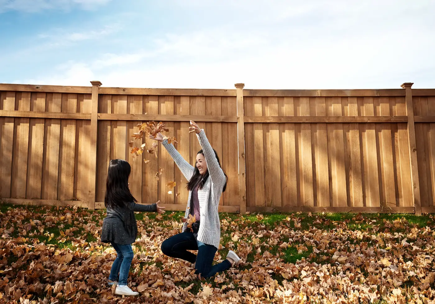 woman and child playing with leaves backyard